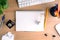 Top view of office desk with paper, stationery, computer, flower, blank notepad and light bulb