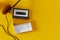 Top view of an old cassette tape and headphones on a yellow background, 3d