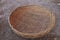 Top view of old threshing basket on rustic muddy ground, woven bamboo, handmade