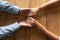Top view older spouses holding hands on wooden table