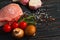 Top view of one pieces raw pork chop steaks with cherry tomatoes Champignon mushrooms on a black stone cutting board