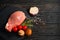 Top view of one pieces raw pork chop steaks with cherry tomatoes Champignon mushrooms on a black stone cutting board