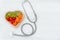 Top view. One single alone red heart love shape with bandage MD medical doctor physician`s stethoscope with vegetable healthy on