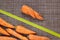 Top view of one ugly twisted carrot and normal vegetables on brown background, zero food waste concept