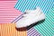top view one white children's sneakers with velcro fasteners on a delicate geometric paper multicolored striped