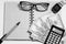 Top view of an open notebook with a pen or pencil, glasses, men`s watch, cash, calculator on a white background