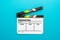 Top view of open white clapperboard on turquoise blue background and copy space