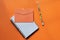 Top view of orange color envelope, notepad and pen