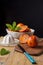 Top view of orange sanginas in bowl with white juicer, mint and blue knife on rustic wooden table and black background