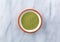 Top view of organic powdered wheat grass in a small bowl on a gray marble counter top