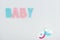Top view of pacifiers and pink and blue baby lettering isolated on white with copy space.