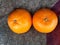 Top view of pair of fresh orange fruit placed on a blanket in daylight.