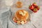Top view of pancakes decorated with pieces of butter and fruit, glass of milk and copper Traditional American breakfast, place for