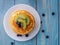 Top view pancakes with topping, kiwi and blueberry.Placed in a white plate on a blue wooden table