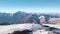 Top view of panorama of rocky mountains with snow on background blue sky. Clip. Snowy slopes with majestic rocky peaks