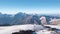 Top view of panorama of rocky mountains with snow on background blue sky. Clip. Snowy slopes with majestic rocky peaks