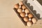 Top view of paper box full of brown raw eggs on the wooden surface, empty space for text