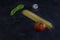 Top view of pasta background with spaghetti ,green pepper,tomato and garlic on floury dark background with copy space for text.