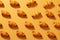 Top view pattern of freshly baked crispy croissants on a vibrant yellow-orange background