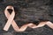 Top view of peach ribbon on dark wood background. Uterine and endometrial cancer awareness concept.
