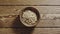 TOP VIEW: Peeled pine nuts fill wooden cup on a wooden table