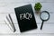 Top view of pen,magnifying glass,plant and book written with FAQs on wooden background.