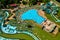 Top view of people relaxing in the pool on yellow inflatable circles and sun beds on the beach