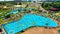 Top view of people relaxing in the pool on yellow inflatable circles and sun beds on the beach