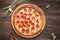 Top view pepperoni pizza on a wooden round board on a wooden background, horizontal