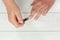 Top view of a person trimming nails with clippers against a wooden surface