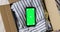 Top view of phone green screen mockup in box with used clothes.