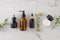 Top view photo of amber cosmetic bottles, cream jar, dropper bottle, face massage roller and eucalyptus leaves