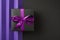 Top view photo of black giftbox with purple ribbon bow on isolated bicolor violet and black background with copyspace