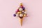 Top view photo of christmas tree balls and sequins flying out of ice cream cone