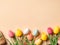 Top view photo of colorful easter eggs small basket and paper-cut tulips on isolated pastel beige background.