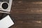 Top view photo of cup of drink on grey laptop white pen two black and white organizers on isolated dark wooden table background