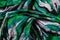 Top view photo of the fragment of multicolored green, black and white colored fabric texture scarf.