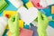 Top view photo of hands in green rubber gloves holding white paper heart multicolor sponges viscose rags garbage bags brush and
