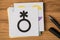 Top view photo of non-binary flag and black genderqueer symbol on stickers and pen on wooden table background