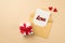 Top view photo of open pastel yellow envelope with card inscription love small red hearts and white giftbox with red ribbon bow on
