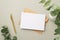 Top view photo of paper sheet craft paper envelope gold pen and white ceramic vase with eucalyptus on pastel grey background with