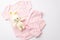 Top view photo of pink infant clothes bodysuit pants and knitted rabbit toy on isolated white background