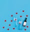 Top view photo of romantic evening, dinner decor hearts love wineglasses with confetti wine bottle on isolated blue background