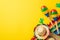 Top view photo of sombrero hats colorful striped serape cactus silhouettes and couple of maracas on vibrant yellow background