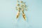 Top view photo of splash of gold christmas decorations from two champagne glasses on  pastel blue background