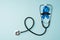 Top view photo of stethoscope and blue ribbon with mustache shape symbol of prostate cancer awareness on isolated pastel blue