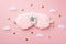 Top view photo of white alarm clock on pink fluffy sleeping mask clouds and golden stars on isolated pastel pink background