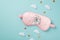 Top view photo of white alarm clock on pink satin sleeping mask clouds and golden stars on isolated pastel blue background with