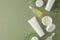 Top view photo of white cosmetic tube, cream jar, dropper bottles and eucalyptus leaves on pastel green background