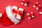 Top view photo of white gift boxes with red ribbon bows flying from santa claus hat on isolated red background